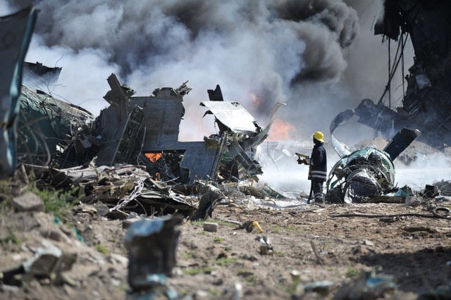 A photograph of a person standing with debris all around him/her and smoke in the background
