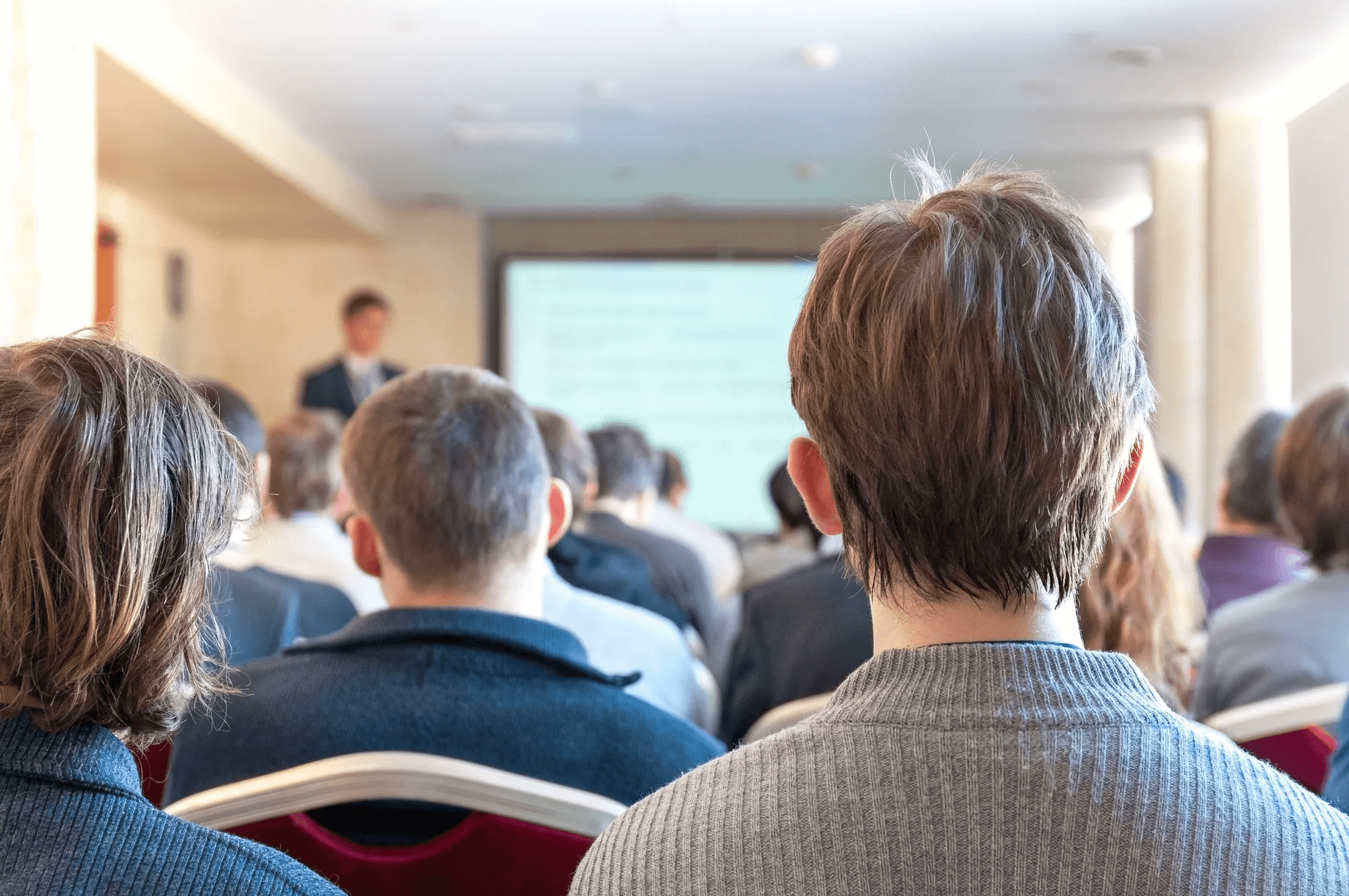 A group of people sitting in front of a projector screen.