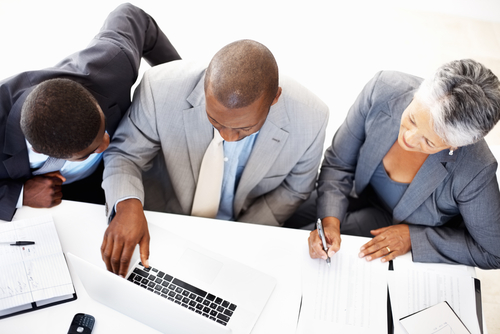 A group of people sitting around a table with laptops.