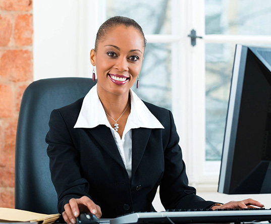 A woman sitting at her desk in front of two computers.