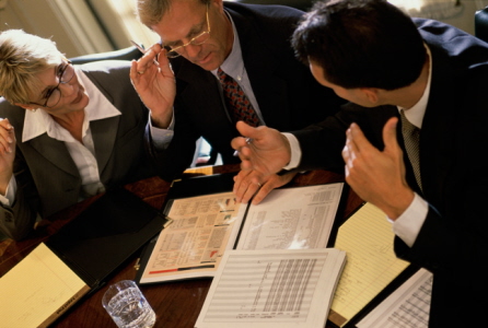 A group of people sitting around a table looking at papers.