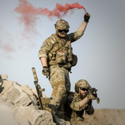 Two soldiers are standing on a hill with smoke coming out of their hands.