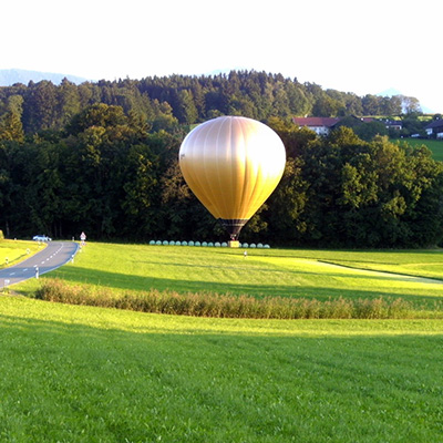 A hot air balloon is flying over the grass.